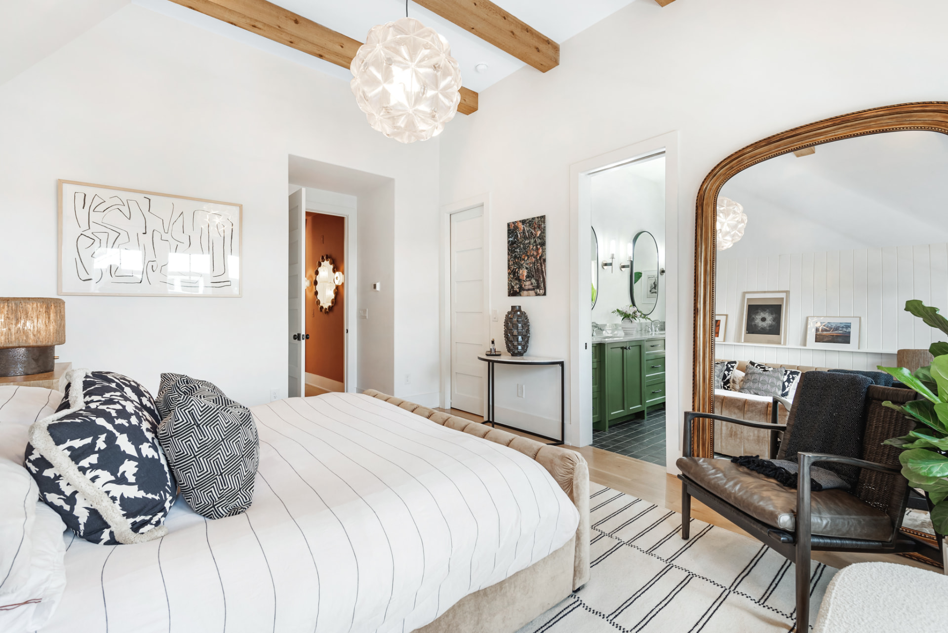 Bedroom looking through to the sage-green ensuite past a gilt arched mirror