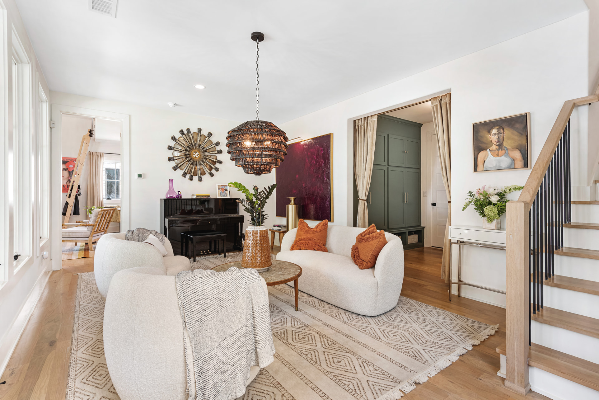 Sitting room with bouclé chairs, a black piano and a crimson canvas