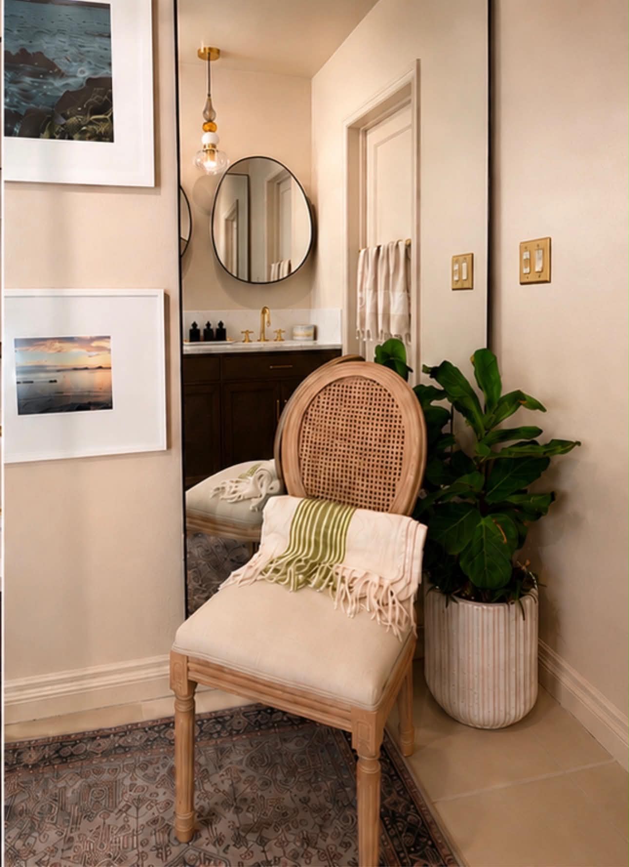 Dressing hall with full-height mirror, caned chair and framed coastal photography