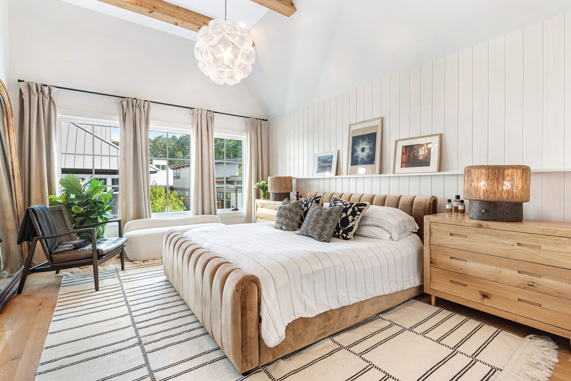 Primary bedroom from the window wall with oak dressers and leaned artwork
