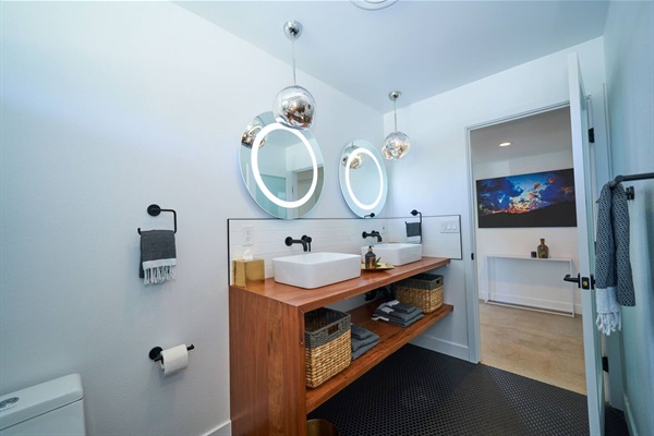 Double vanity in walnut with vessel basins and lit round mirrors