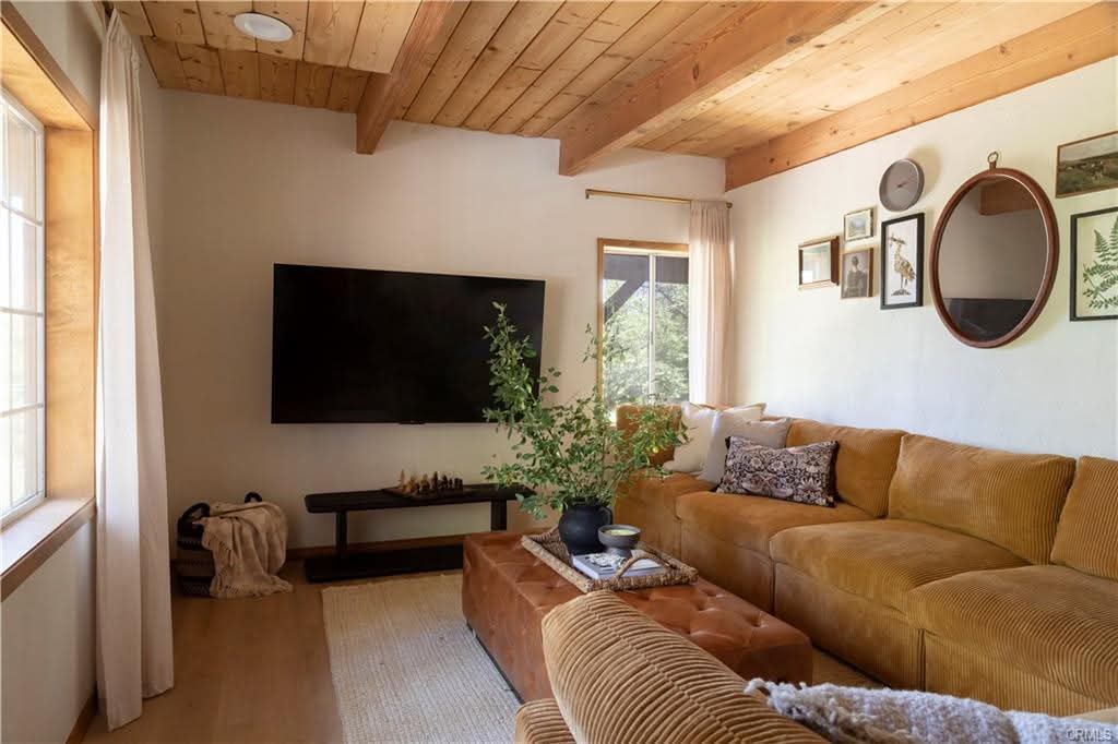 Living room with caramel corduroy sectional, leather ottoman and gallery wall