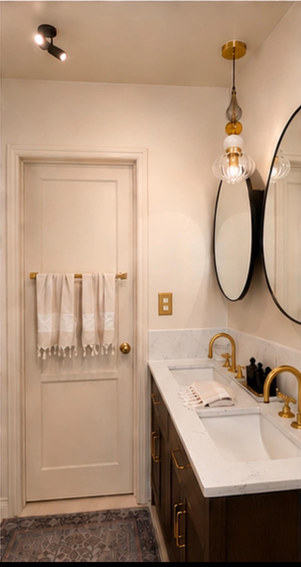 Bath entry with brass towel bar, panelled door and twin oval mirrors