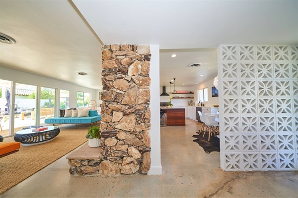 Breeze-block screen and stone column dividing living room and kitchen