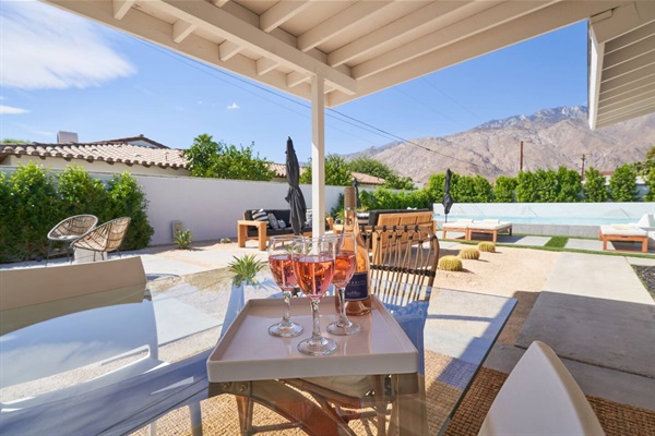 Covered patio with rosé on a glass table and the San Jacintos beyond