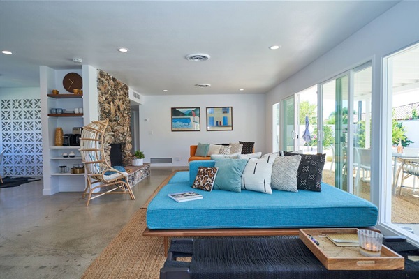 Living room with stone fireplace, breeze-block screen and turquoise daybed