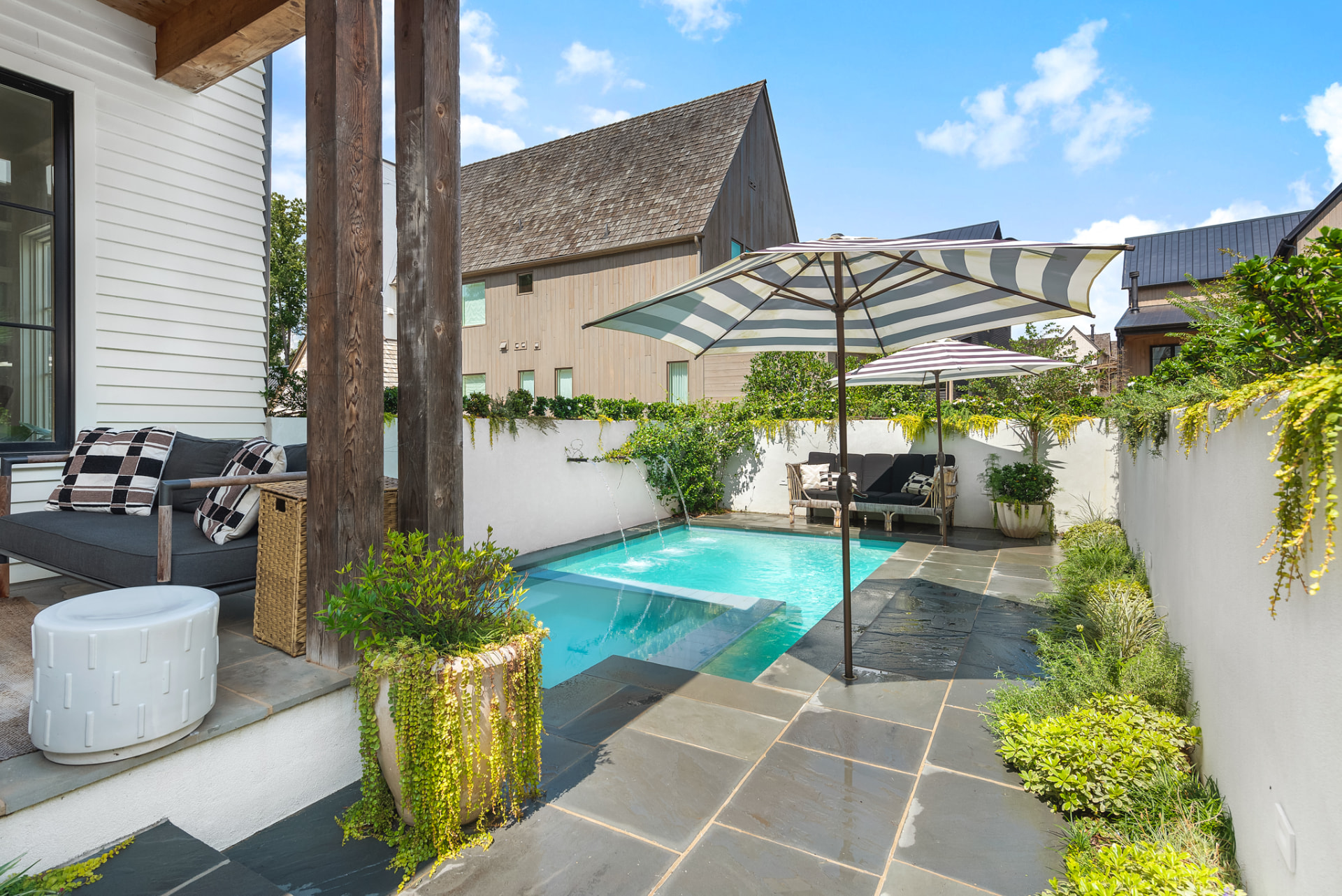 Pool terrace under striped umbrellas looking back to the house