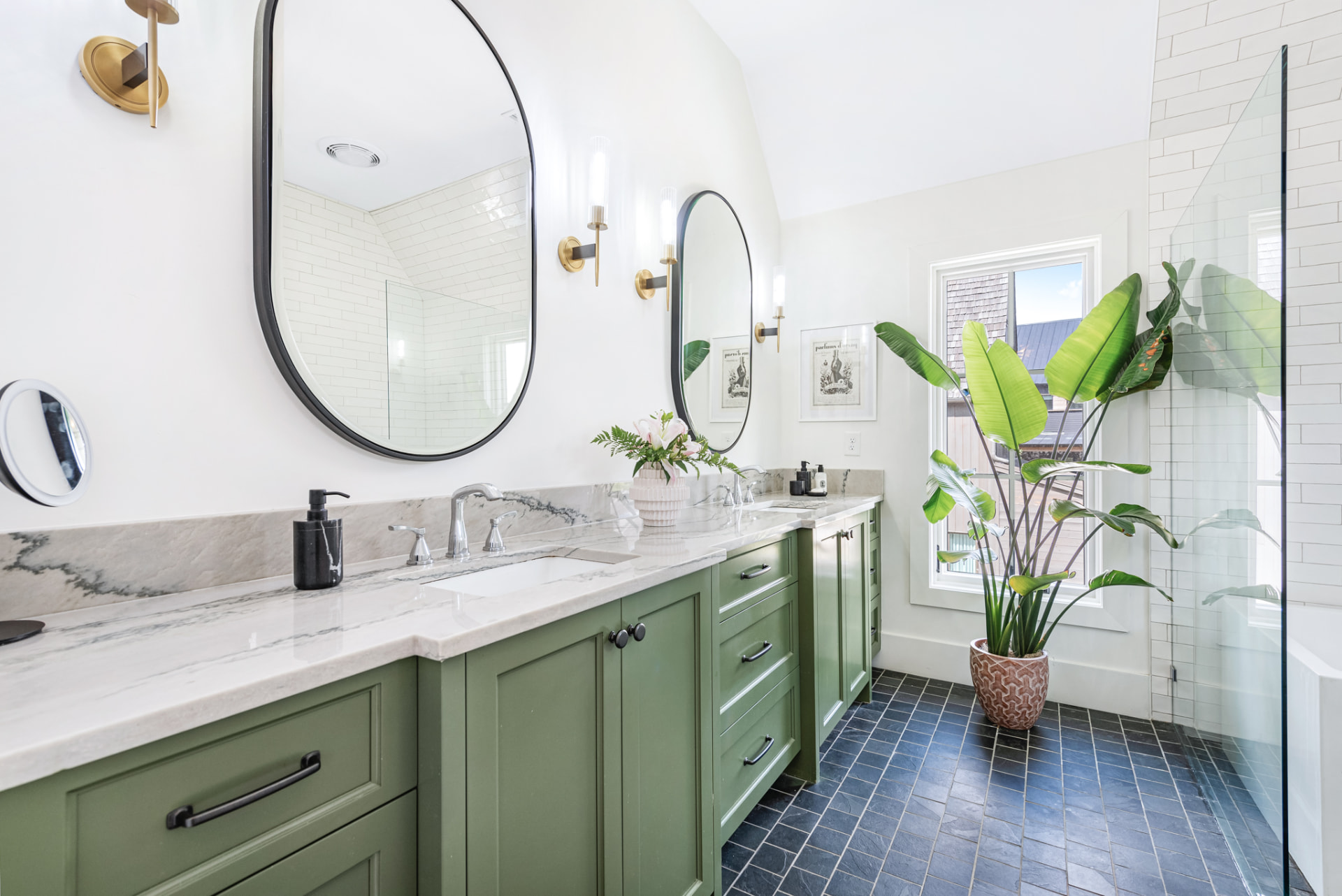 Primary bath with sage-green vanity, marble counter and black oval mirrors