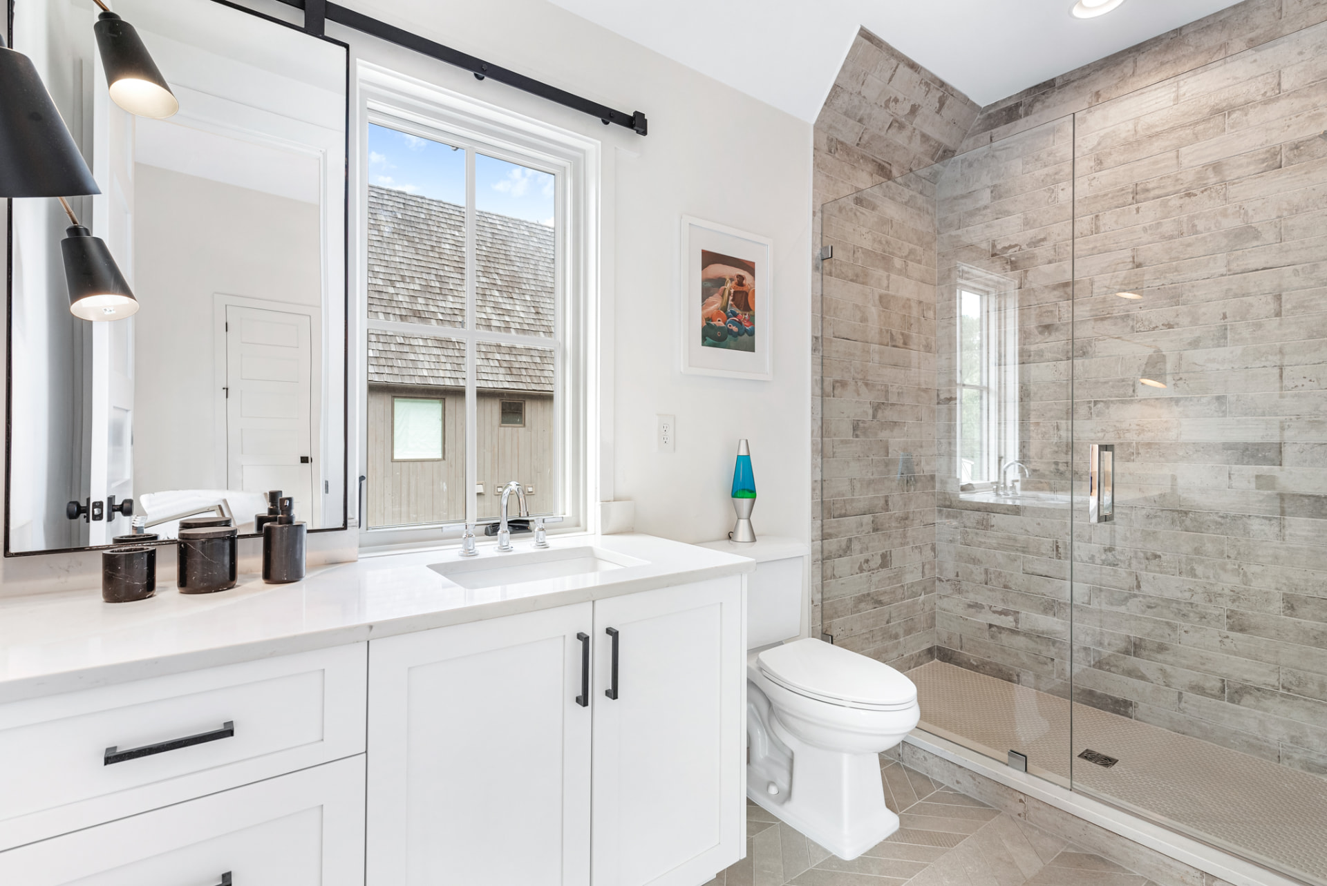 Guest bath with white shaker vanity, black hardware and stone-look tiled shower