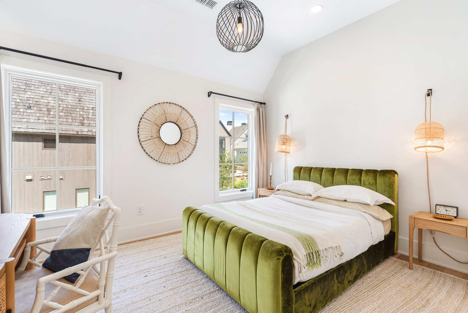 Guest bedroom with olive velvet channelled bed, rattan sunburst mirror and woven sconces