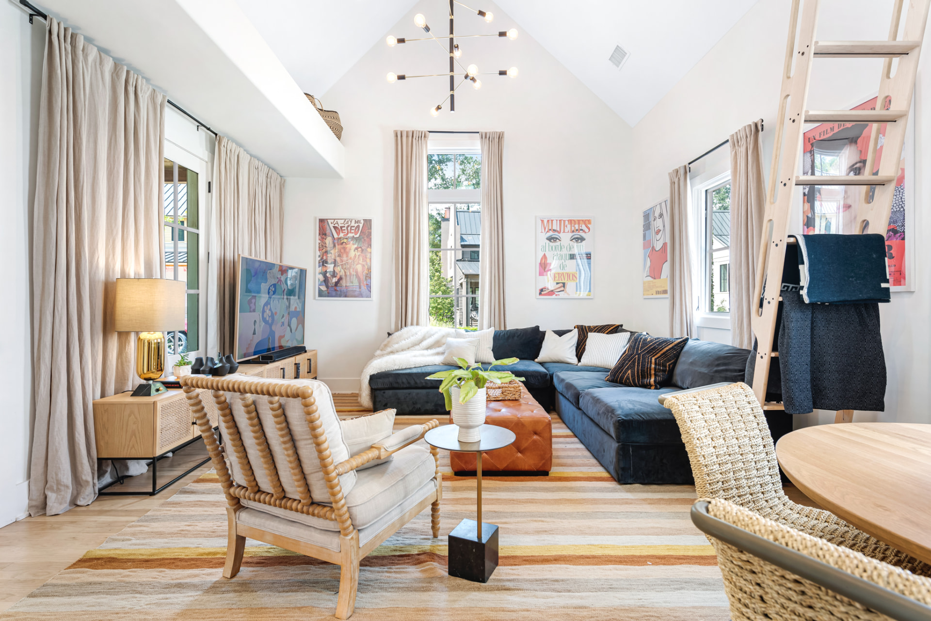 Vaulted great room with teal velvet sectional, ochre striped rug and framed film posters