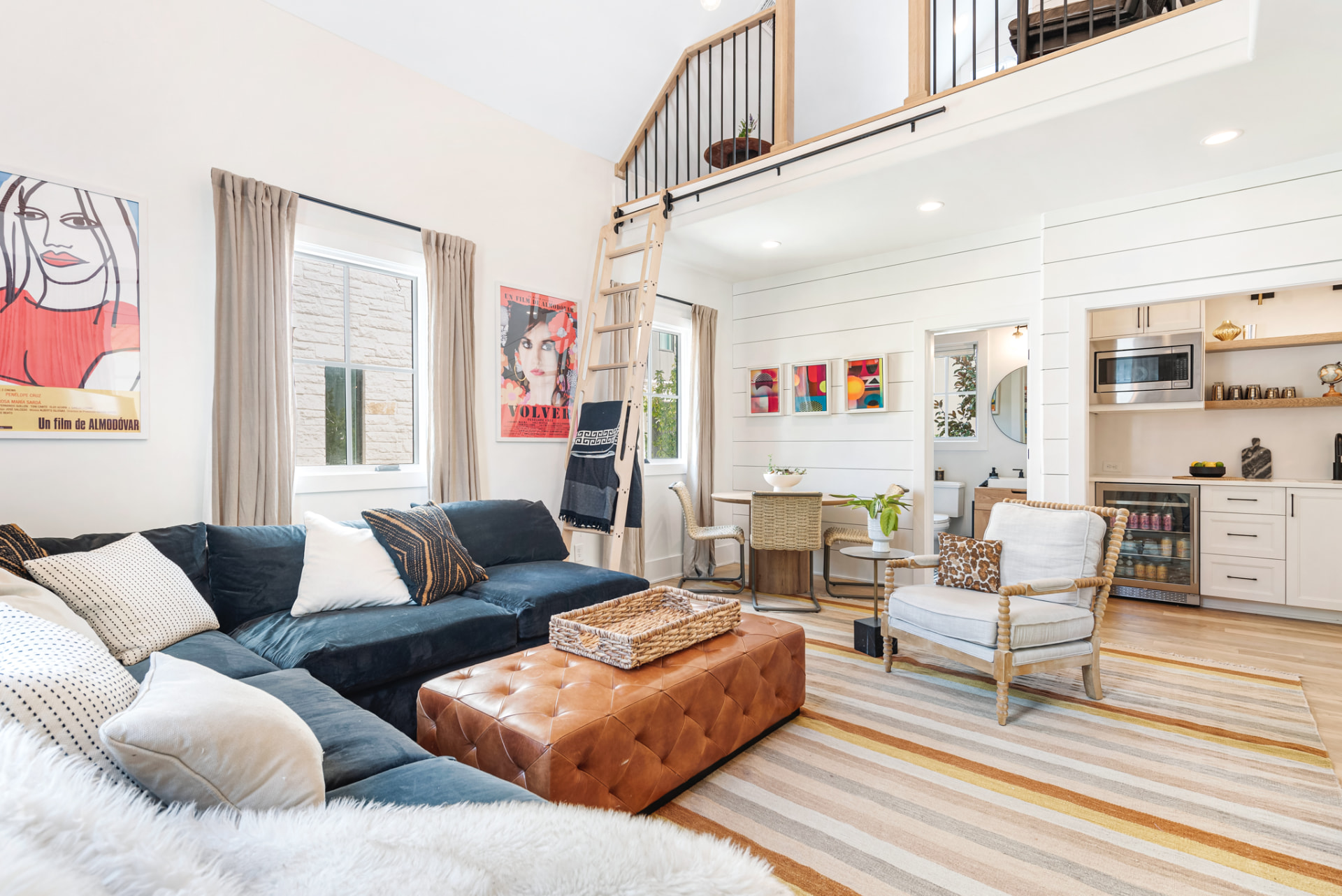 Great room with leather ottoman, library ladder to the loft and shiplap kitchenette