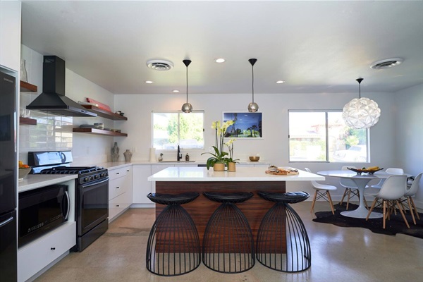 Range wall with walnut shelves, wire stools and cloud-form pendant over the dining table