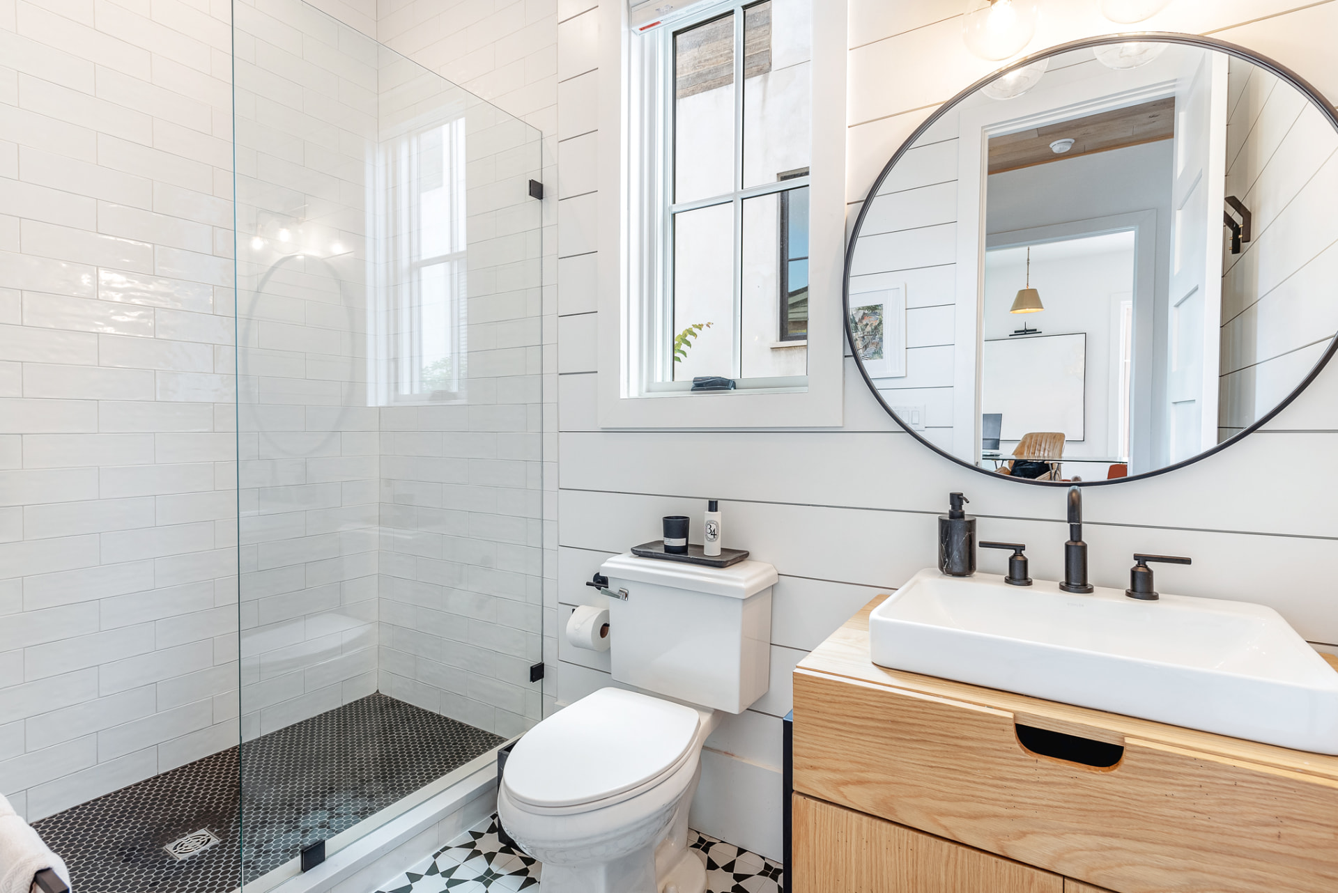 Bath with glass shower, black penny-round floor and oak vanity