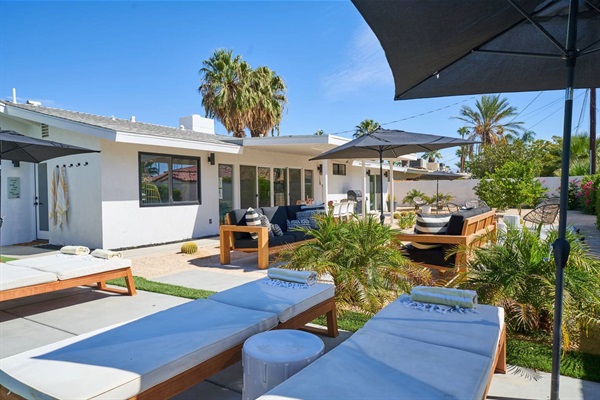 Poolside courtyard with teak seating, chaises and parasols