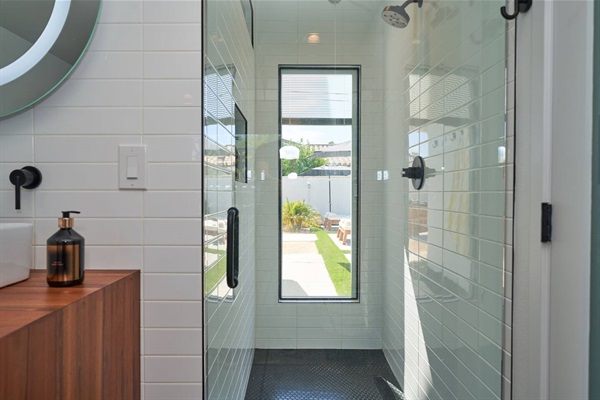 Glass shower with stacked white tile, penny-round floor and slot window