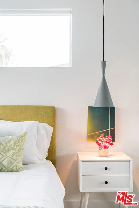 Bedside vignette with white nightstand, blooms and cone pendant