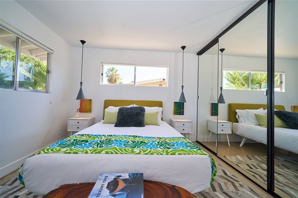 Bedroom with chartreuse headboard, twin grey cone pendants and mirrored wardrobe