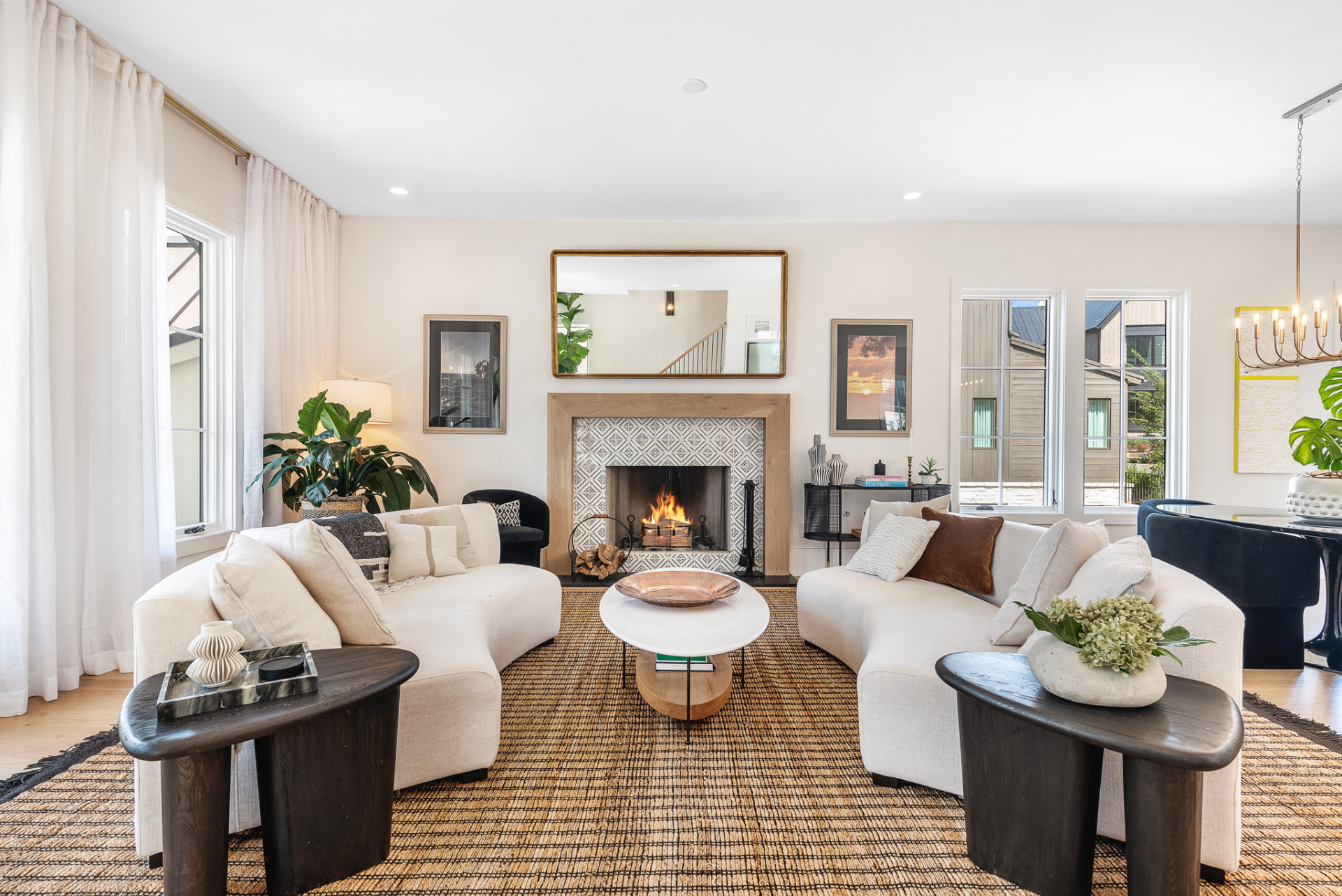 Living room with curved ivory sofas facing a patterned tile fireplace