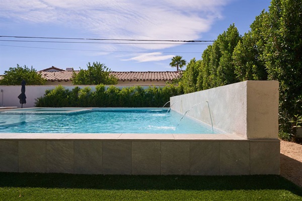 Plaster spa wall with twin water scuppers spilling into the pool
