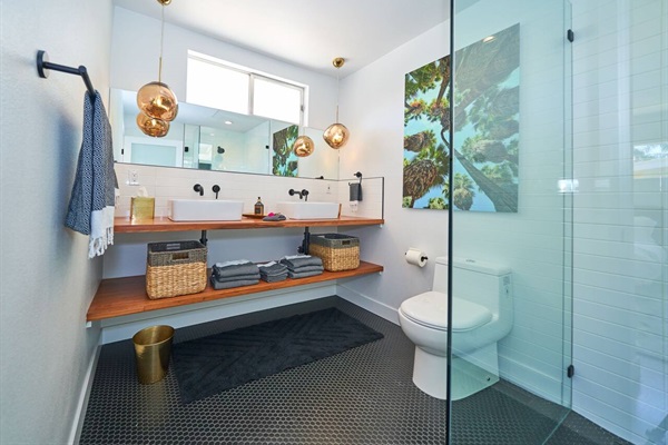 Guest bath with floating walnut shelf, copper pendants and penny-round floor