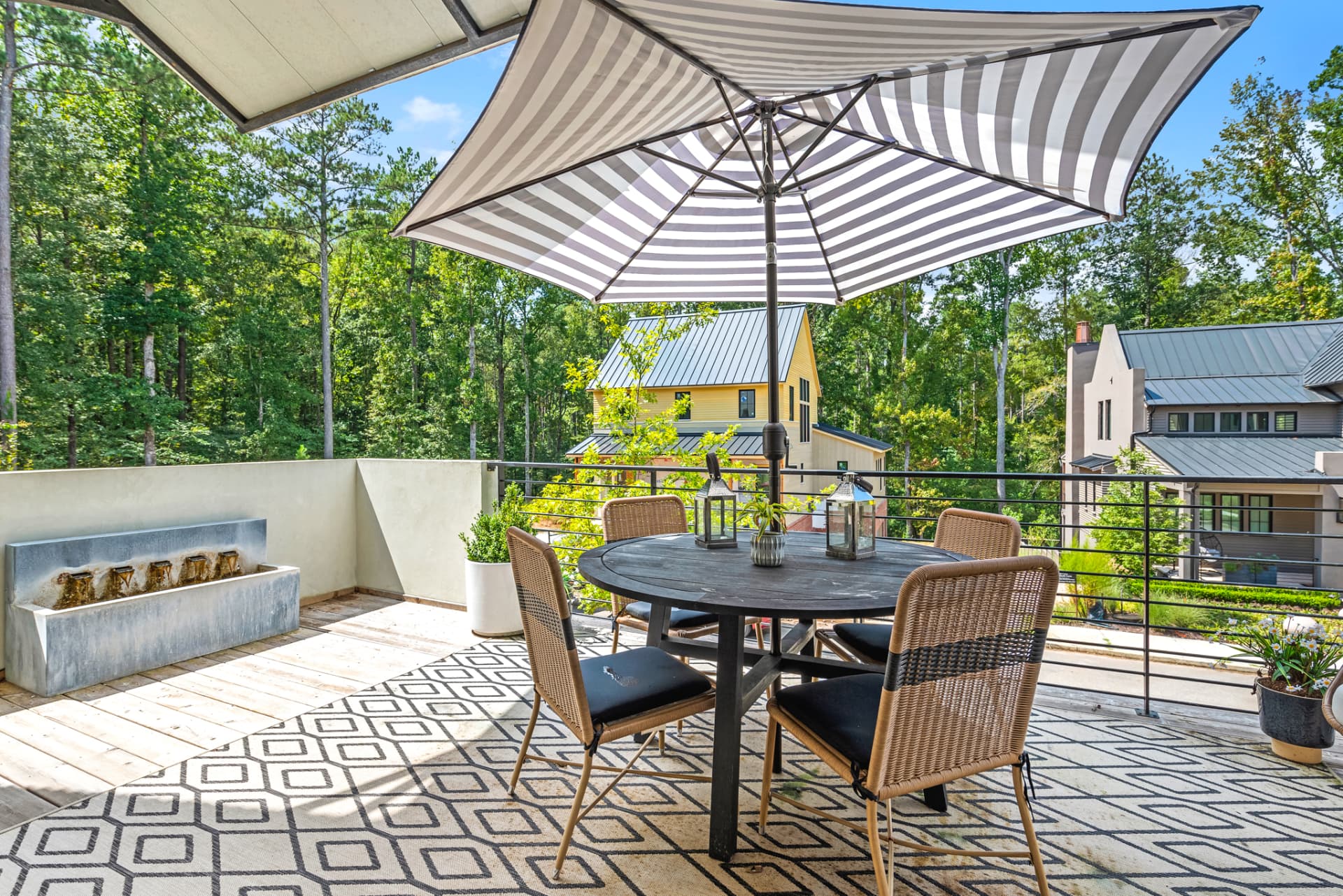 Terrace with striped umbrella, stone water feature and outdoor dining