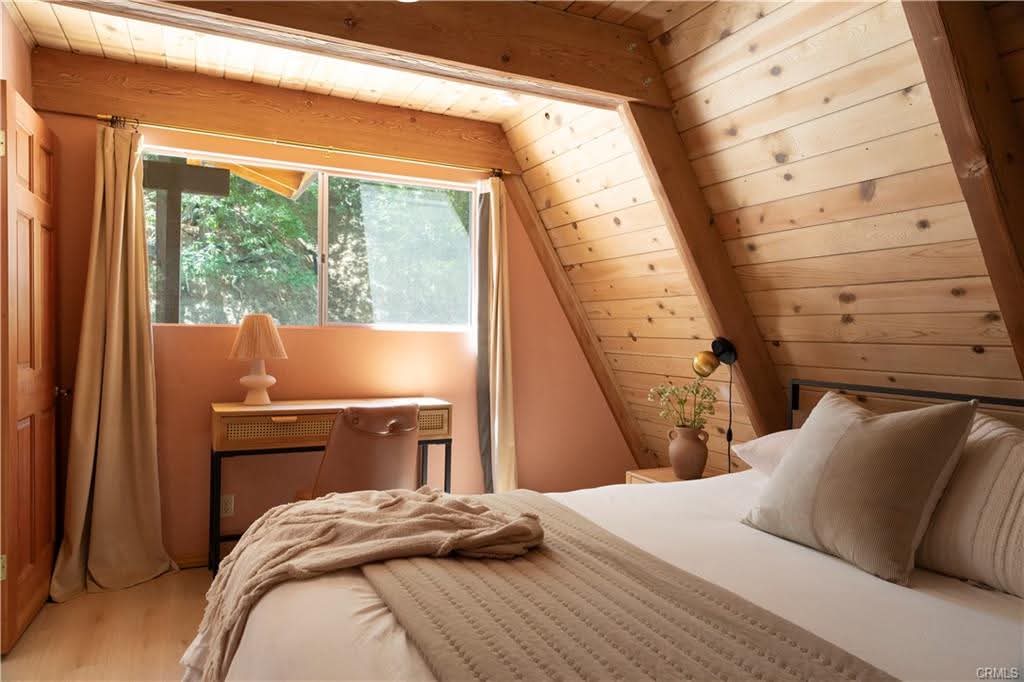 Bedroom with caned desk, terracotta lamp and forest view through the window