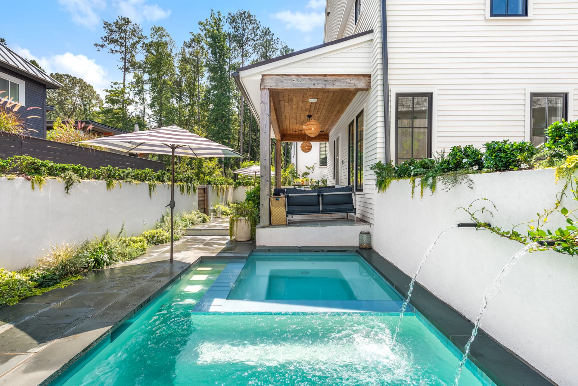 Pool with stone fountain wall and shaded outdoor seating