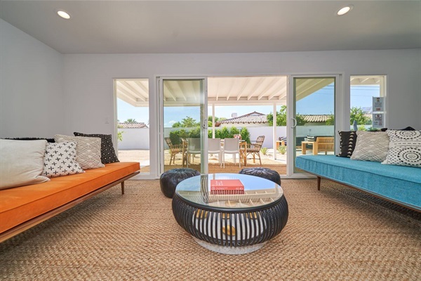 Facing daybeds in orange and turquoise with drum table and patio beyond
